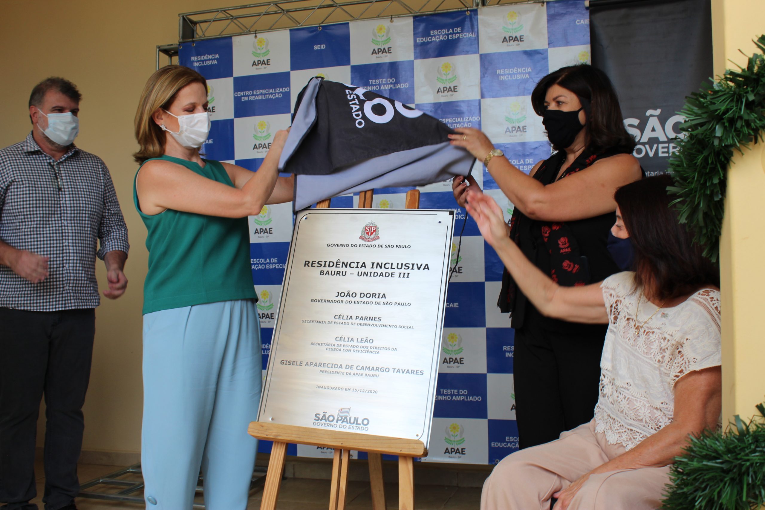 Foto colorida do momento histórico com a placa de inauguração da terceira residência inclusiva da APAE Bauru. Na foto: o prefeito Clodoaldo Gazzetta, a Secretária do Desenvolvimento Social, Célia Parnes, a presidente da APAE Bauru Gisele de Camargo Tavares e a Secretária dos Direitos da Pessoa com Deficiência, Célia Leão.